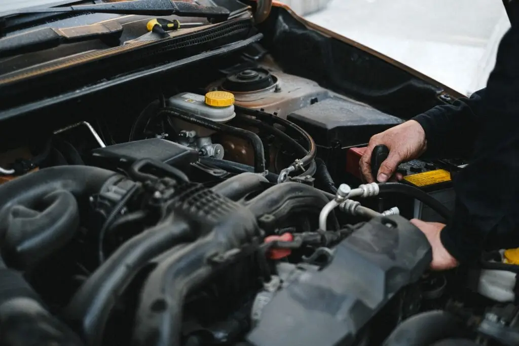 Hands working under the bonnet of a car during engine-bay maintenance