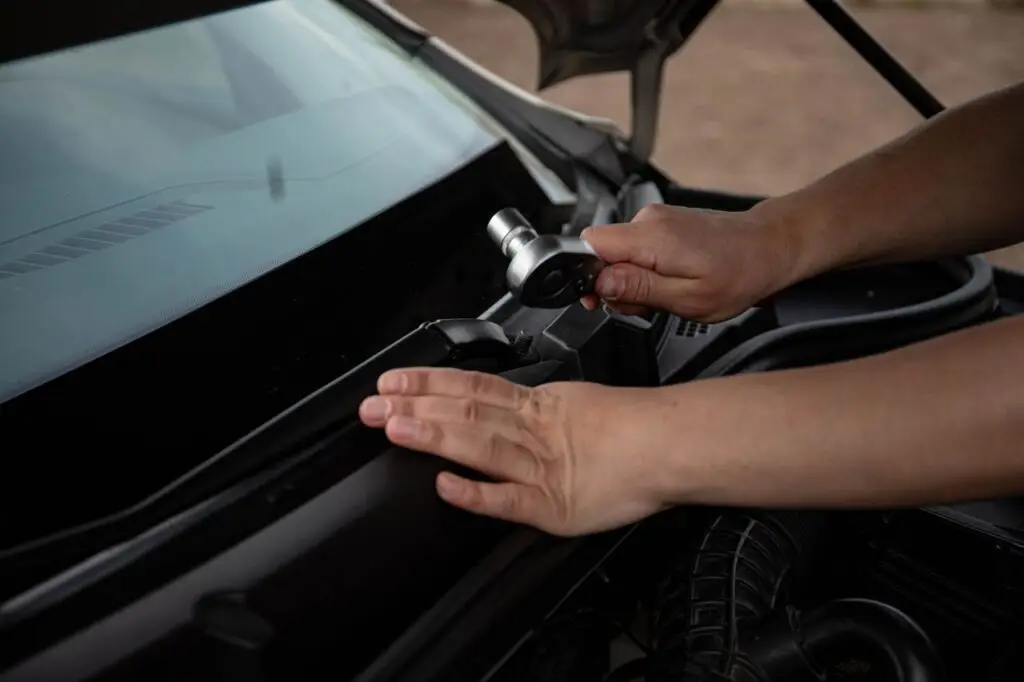 Hands using a ratchet and socket on a windscreen-wiper fastener