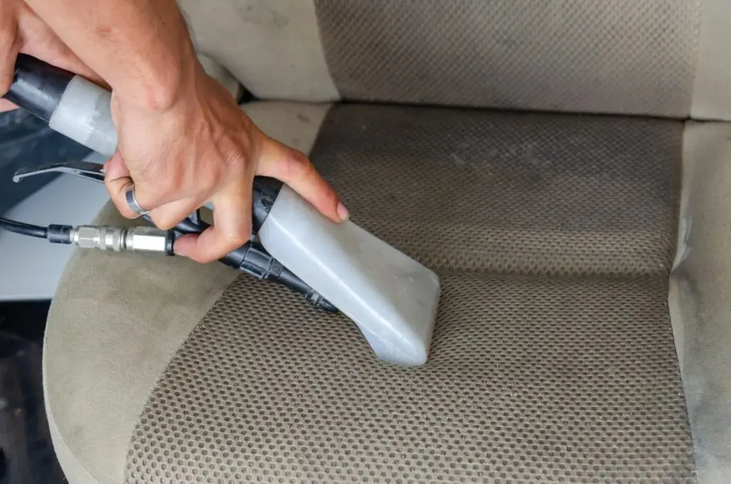 Cleaning a fabric car seat with an upholstery extraction nozzle