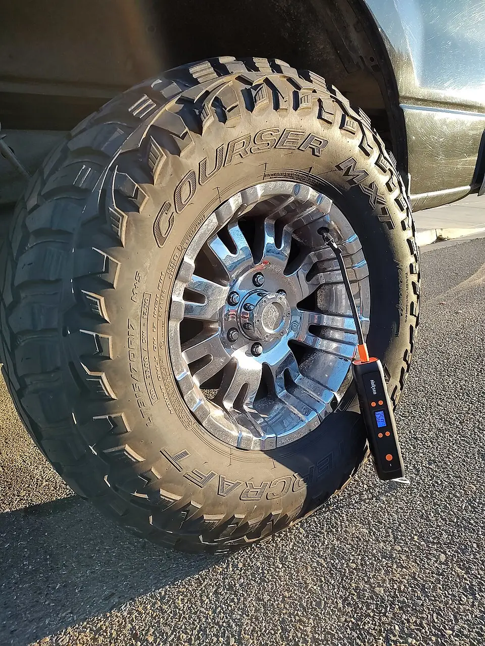Cordless pump connected to a tire valve, illustrating how to use a portable tire inflator.