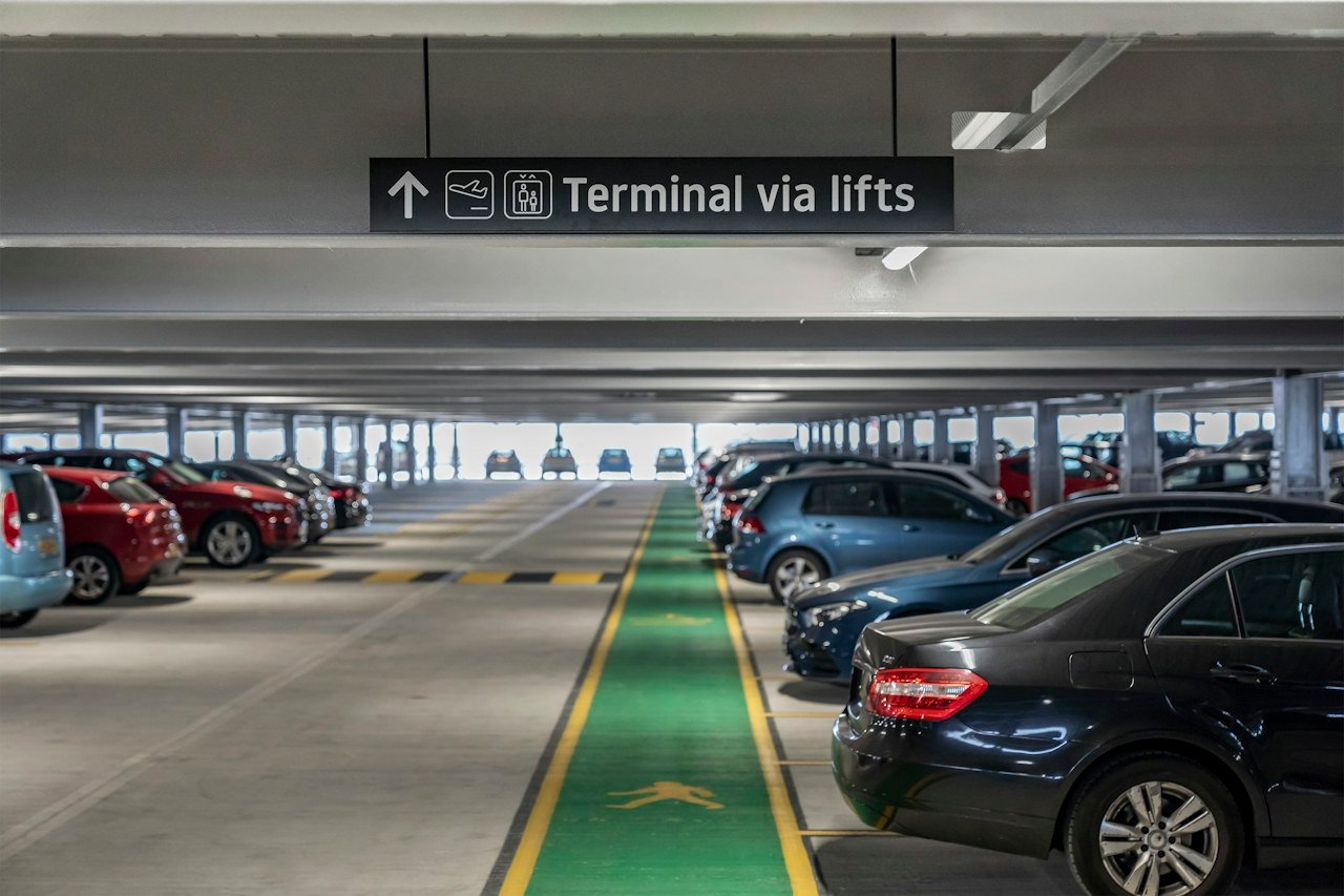 Cars parked beside a pedestrian walkway in an airport car park