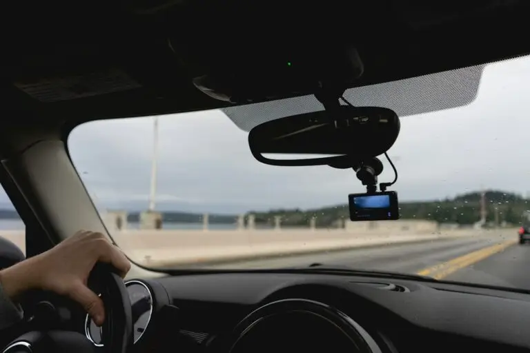 A dash camera mounted below a rear-view mirror during highway driving